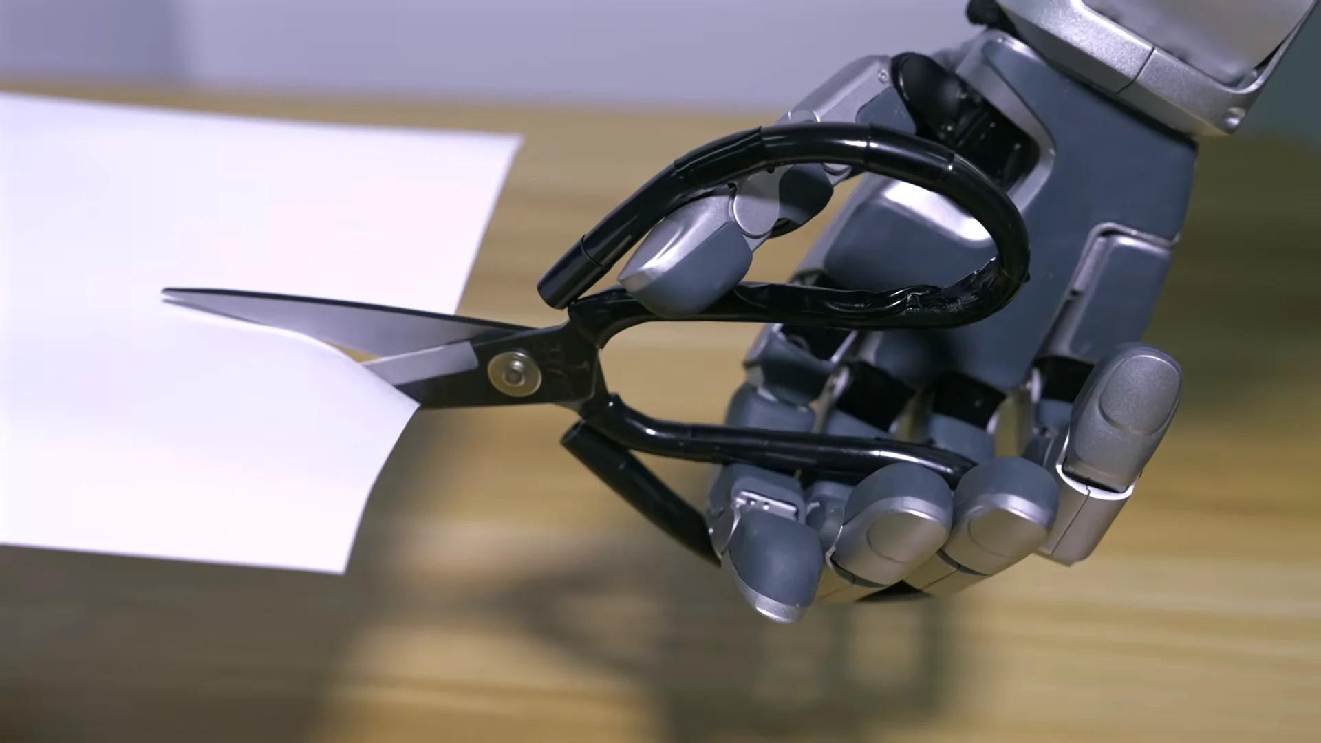 Holds scissors with a human grip and cuts paper.